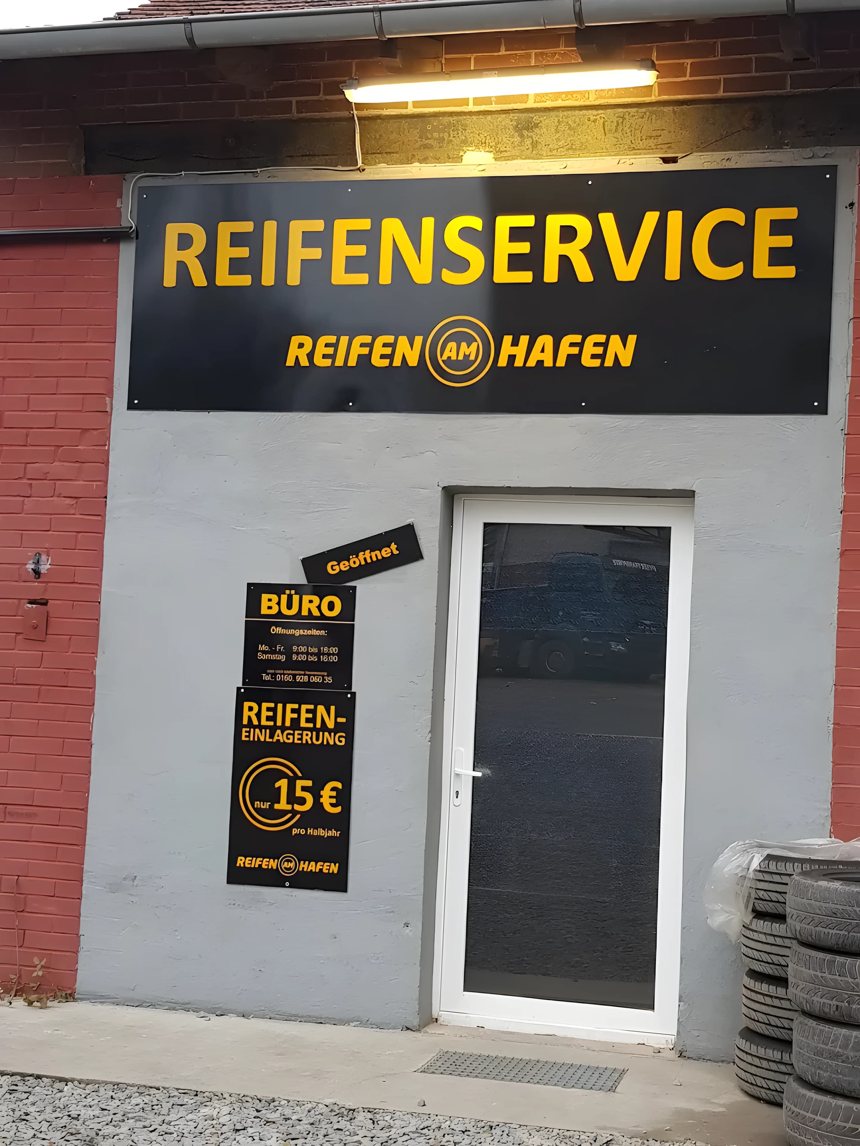 Eingang von Reifen am Hafen: schwarzes Schild mit gelber Aufschrift Reifenservice über der Bürotür